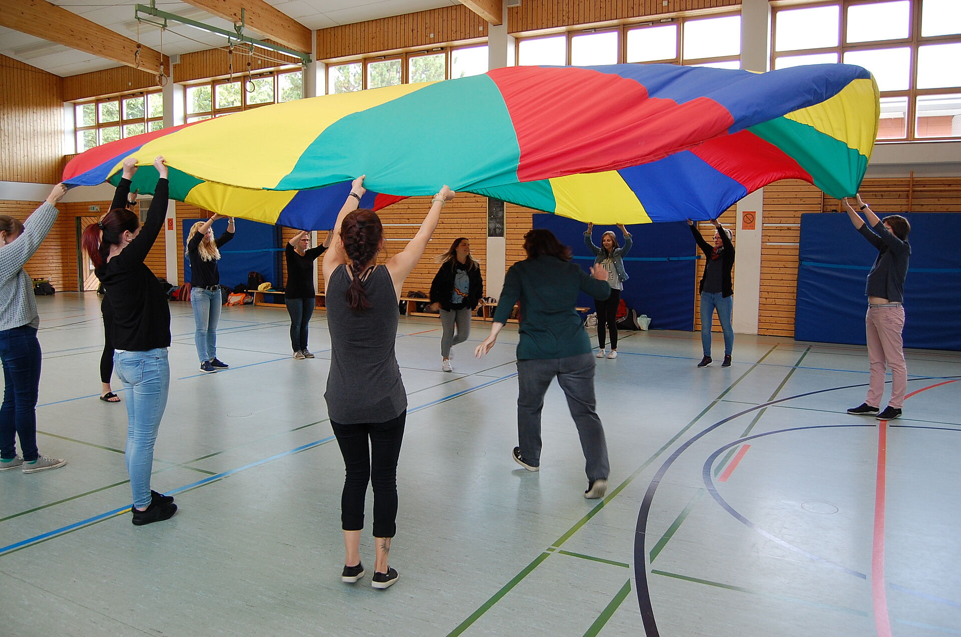 Studierende der Heilpädagogik befinden sich in einer Sporthalle und üben mit einem Schwungtuch